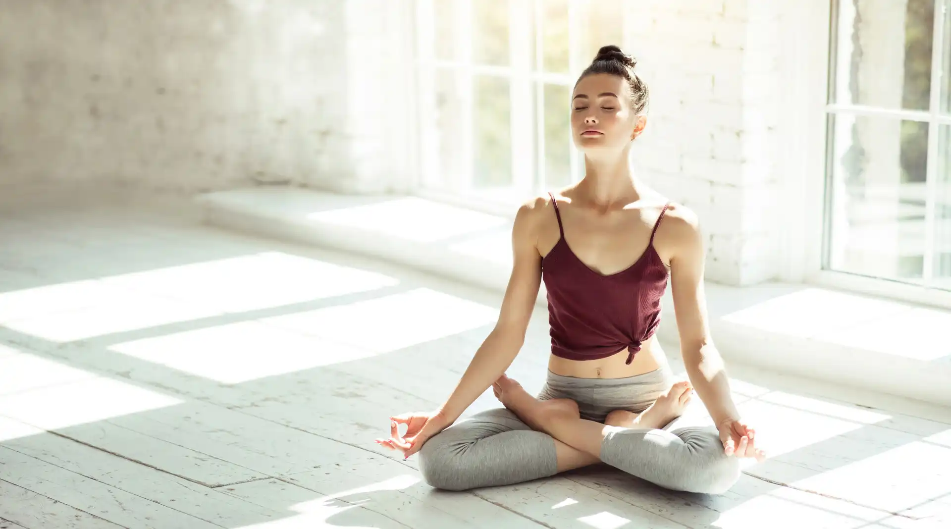 persona meditando en posición de loto, fotografía profesional en tonos suaves